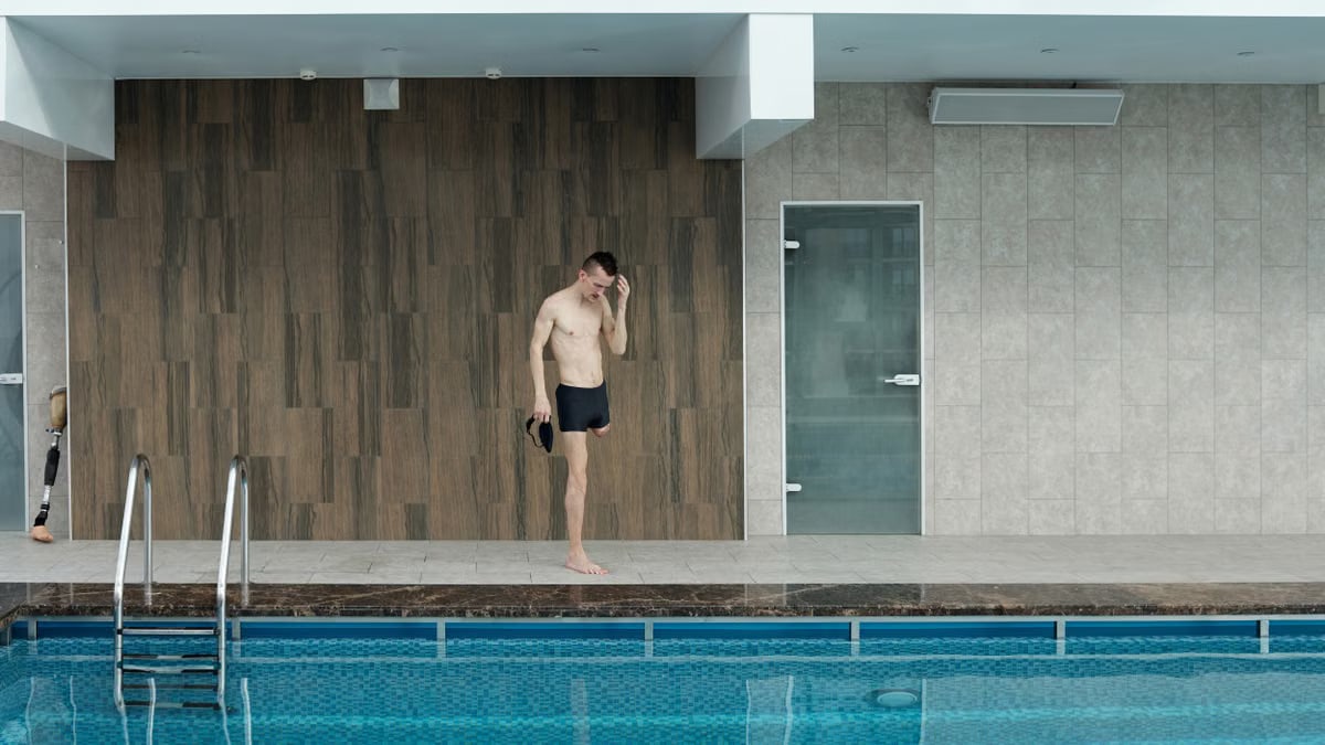 Amputee athlete preparing at an indoor swimming pool, portraying determination and fitness.